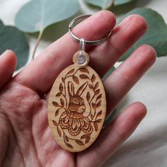 a hand holding a wooden keychain with an animal on it