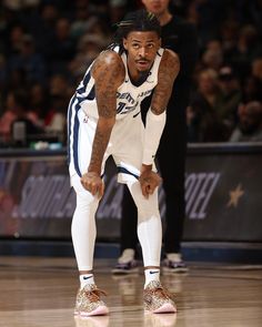 a basketball player with his hands on his knees looking down at the floor while standing in front of an audience