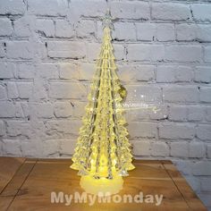 a lighted glass christmas tree on a wooden table