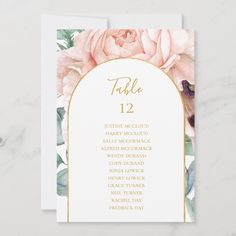 a table card with pink flowers and gold foil on the top, in front of a marble background