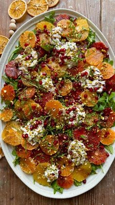 a white plate topped with oranges and other food on top of a wooden table