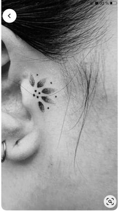 a black and white photo of a woman's ear with a flower tattoo on it