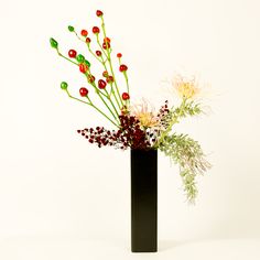 a black vase filled with lots of different types of flowers