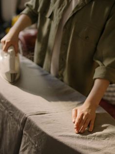 a person ironing fabric on an ironing board with a hand holding the iron