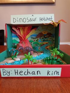 a dinosaur habitat in a cardboard box on a table