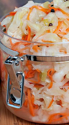 a bowl filled with coleslaw and carrots on top of a wooden table