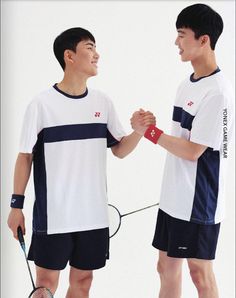 two young men shaking hands while holding tennis racquets in front of each other