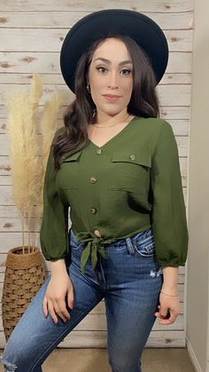 a woman in jeans and a hat poses for the camera with her hands on her hips