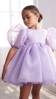 The most perfected magical short puff sleeve lavender dress. Perfect for any occasion, it's subtle & elegant yet fun! This voluminous puff sleeve dress has a layered organza, a round high neckline, with a v-low back brought together by a lavender pearl button.  Bloomers included for sizes 6m-7yrs.    COMPOSITION OU Lilac Dress Kids Casual, Organza Dress Puff Sleeve, Organza Outer, Lavender Dress, Short Puff Sleeve, Lavender Dresses, Puff Sleeve Dress, Puffed Sleeves Dress, Babydoll Dress