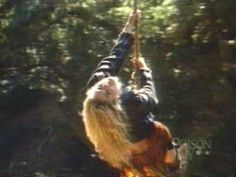 a woman is swinging on a rope in the air with her hair blowing back and forth