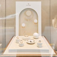 a display case with jewelry on it in front of a glass wall and other items