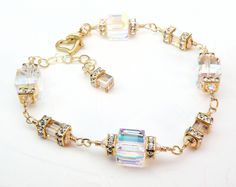 Beautiful modern wedding bracelet is handmade with very sparkly Swarovski crystals in a clear hue. Accented with gold Swarovski crystal crowns and small champagne hued cubes. Set in 14k gold filled findings. Opulent bracelet perfect for brides on wedding days, mother of the bride, or just days you want to sparkle more than usual. A thoughtful gift for a woman born in April since diamond is her birthstone. Bracelet Details: - Choose sterling silver or 14k gold filled - Bracelet is adjustable for Gold Crystal Bracelet With Bling For Wedding, Gold Bling Bracelets For Wedding, Anniversary Crystal Bracelet With Sparkling Stones, Crystal Faceted Bracelets For Weddings, Elegant Clear Wedding Bracelets, Gold Faceted Bracelets For Wedding, Sparkling Crystal Bracelet For Anniversary, Faceted Gold Bracelets For Wedding, Sparkling Gold Bracelets For Anniversary