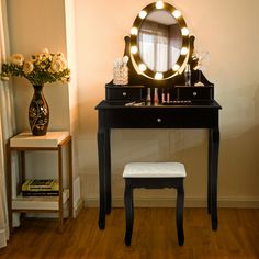 a vanity with a mirror and stool in front of a window on a wooden floor