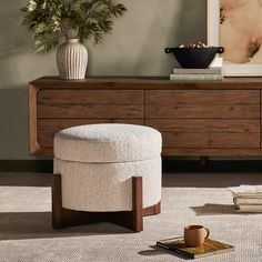 a white ottoman sitting on top of a rug next to a wooden dresser