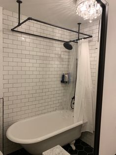 a white bath tub sitting next to a toilet under a light fixture in a bathroom