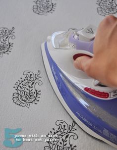 a person ironing fabric with an electric iron on it's side while pressing buttons