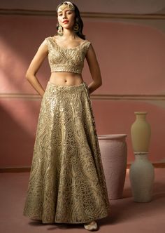 This lehenga set features heavy gold zari embroidery with mirrorwork. The short sleeves blouse has a plunging neckline. The lehenga set shows delicate tassels details. It is paired with a mirror embroidered organza dupatta with tassels on both sides. Gold Pre-draped Saree With Intricate Embroidery For Reception, Gold Floor-length Palazzo Set For Reception, Gold Dress With Mirror Work For Reception, Gold Floor-length Palazzo Set With Zari Work, Gold Traditional Wear With Mirror Work For Reception, Gold Floor-length Palazzo Set For Designer Wear, Gold Lehenga With Mirror Work For Reception, Gold Lehenga Saree With Mirror Work, Designer Gold Pre-draped Saree With Intricate Embroidery