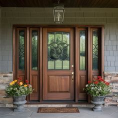 two large planters with flowers are on the front steps of a house that has glass doors