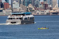 a boat with people on it is in the water near a large cityscape