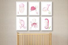 four pink sea animals are hanging on the wall above a crib in this baby's room