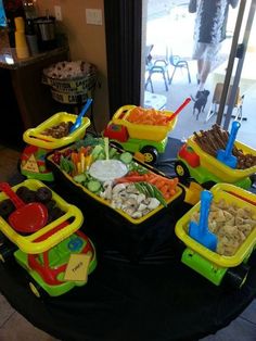 several trays filled with different types of food on top of a black cloth covered table