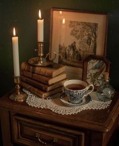 a table topped with books and a cup filled with tea next to a candle holder