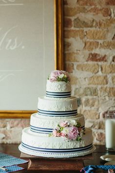 a wedding cake sitting on top of a wooden table next to a framed sign and candles