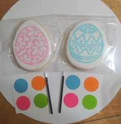 two decorated cookies sitting on top of a plastic bag next to some markers and stickers