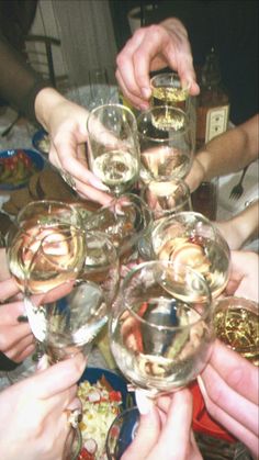 many people are holding wine glasses together