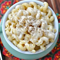 a bowl filled with macaroni and cheese on top of a colorful place mat