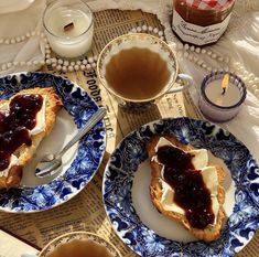 two plates with food on them sitting on a table next to cups and saucers