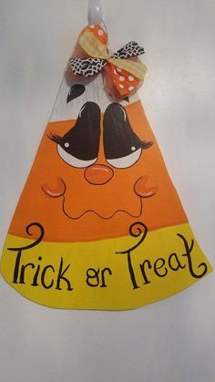 an orange and yellow trick or treat sign with a bow on it's head