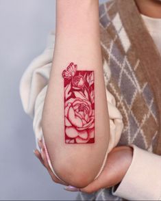 a woman's arm with a red rose and butterfly tattoo on it