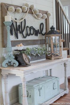 a welcome sign on the wall above a table with an old trunk and lantern in it