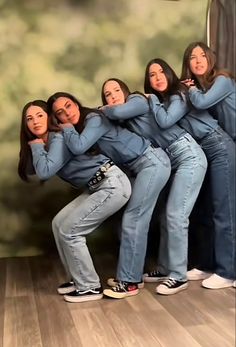 four women are posing in front of a wall with their hands on their hipss