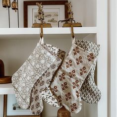 two christmas stockings hanging from hooks on a white shelf in a room with other items