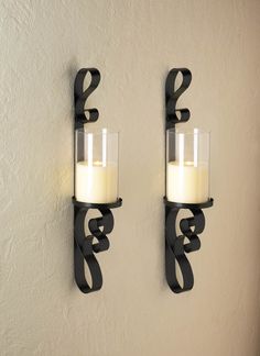 two candle holders on the wall next to each other