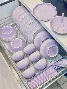 purple dishes and plates are stacked in a drawer