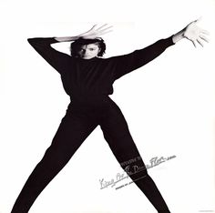 a man in black is dancing with his arms stretched out and hands extended to the side