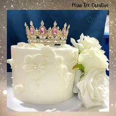 a wedding cake with a tiara on top and flowers next to it in front of a blue background