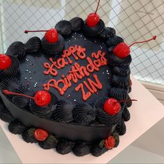 a heart shaped birthday cake with the words happy birthday zn on it and cherries