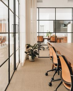 an empty conference room with wooden tables and chairs in front of large glass doors that look out onto the outdoors