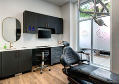 an office with black cabinets and chairs in front of a large window that looks out onto the street