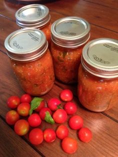 several jars filled with tomatoes on top of a wooden table