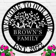 a metal sign that says welcome to our brown's family with flowers in front of it