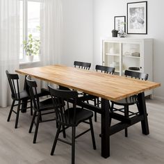 a wooden table with black chairs in a white room