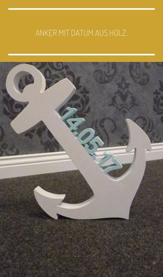 an anchor and name sign sitting on the floor in front of a wallpapered background