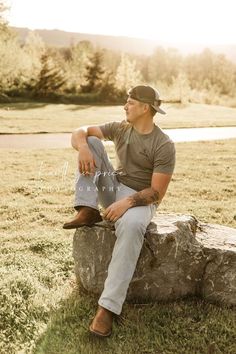 a man sitting on top of a rock in the grass