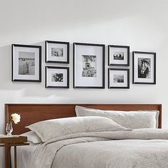 a bed with white sheets and pictures on the wall above it