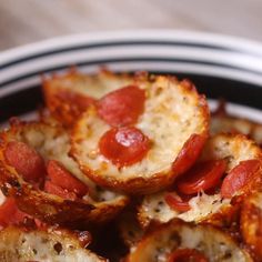 small slices of bread with pepperoni and cheese on them in a black and white bowl